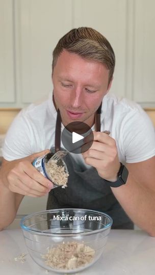 a man in an apron mixing food into a bowl with a measuring cup and spoon