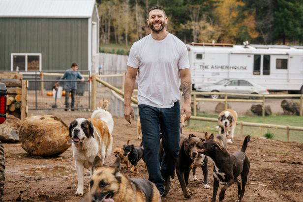 a man is walking with many dogs in the dirt