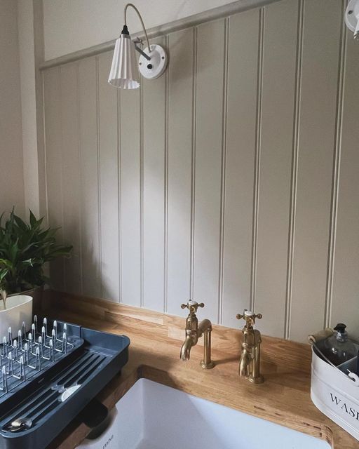 two faucets sitting on top of a wooden counter next to a white sink