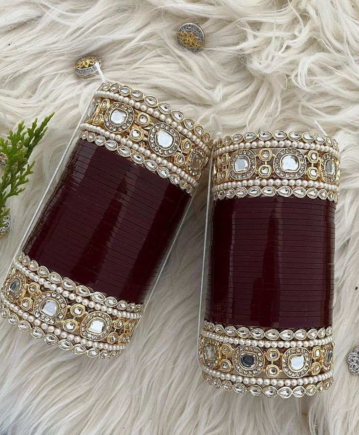 two red and gold cuff bracelets sitting on top of a white fur covered floor