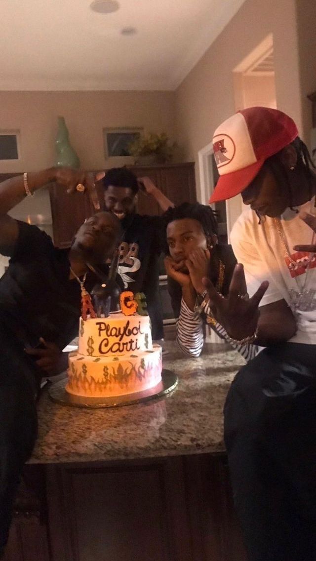 three people sitting at a counter with a cake in front of them and one person pointing to the side