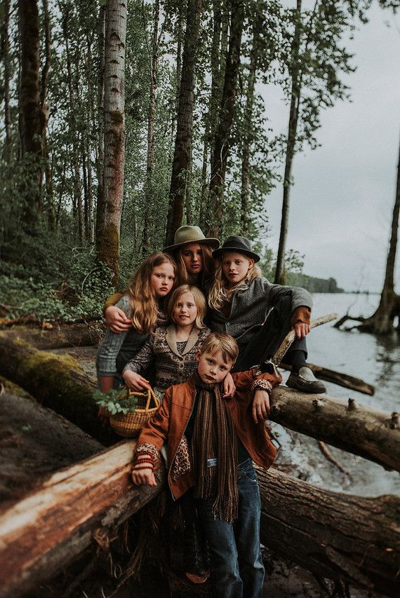 a group of people standing next to each other on a log in the middle of a forest