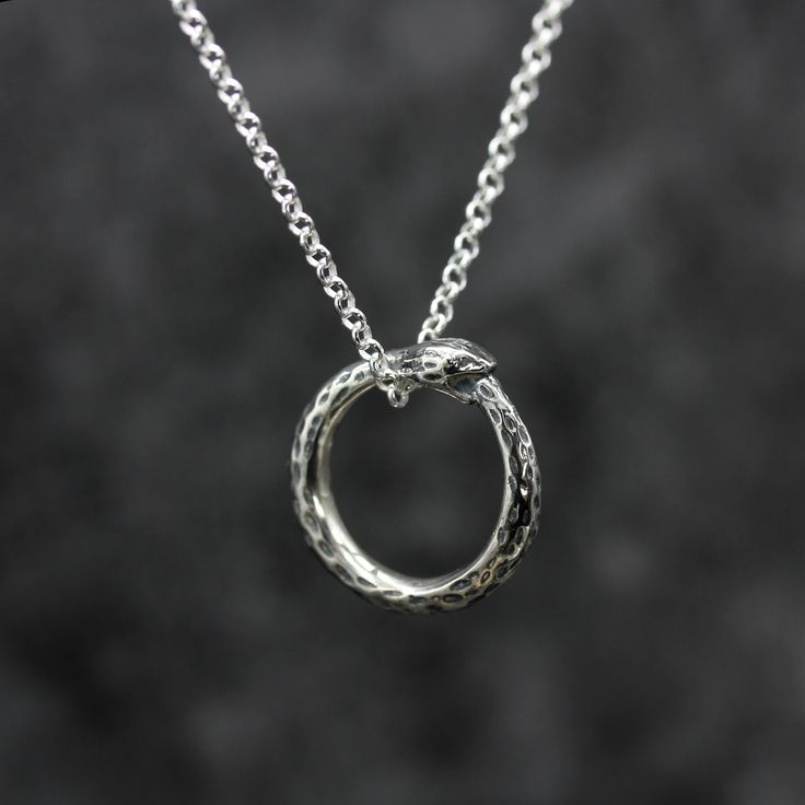 This timeless design reflects the continuous cycle of life and carries a strong symbolic meaning of eternity and self-reflection. Wear it to bring a unique and meaningful accent to your style. Originally handmade, now cast into silver, we finish each and everyone of our ouroboros snake necklaces by hand in our Birmingham Jewellery Quarter workshop. ⸸ Pendant: 20mm x 20mm⸸ Weight: approximately 9.1 g including chain⸸ Chain: 22 inches⸸ 3 - 5 working days Ouroboros Meaning, The Worm Ouroboros, Ouroboros Earrings, Ouroboros Necklace, Spiritual Silver Snake Necklace, Ouroboros Snake, Birmingham Jewellery Quarter, Snake Necklace, Silver Wedding Rings