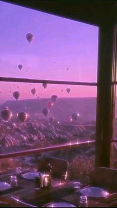 a table with plates and cups on it in front of a window overlooking hot air balloons