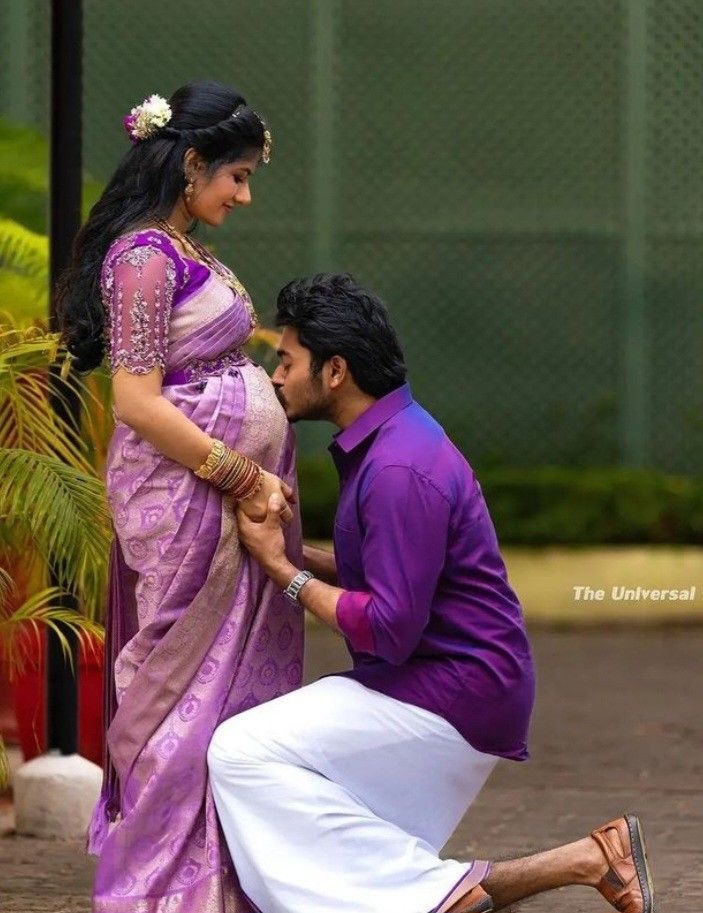 a man kneeling down next to a woman in a purple sari and white pants