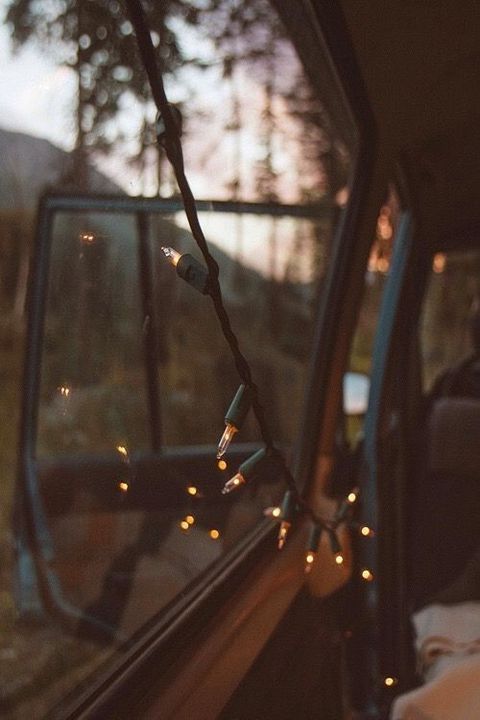 the interior of a vehicle with christmas lights hanging from it's side window at night