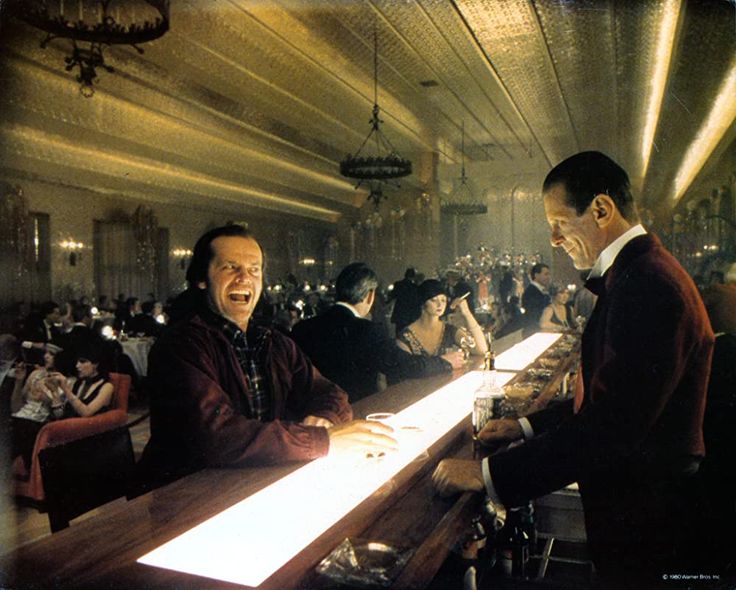 two men sitting at a bar with people in the background