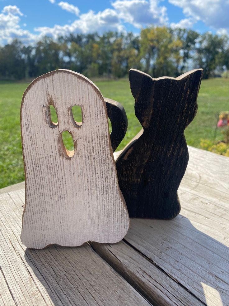 two carved wooden ghost heads sitting on top of a wooden table