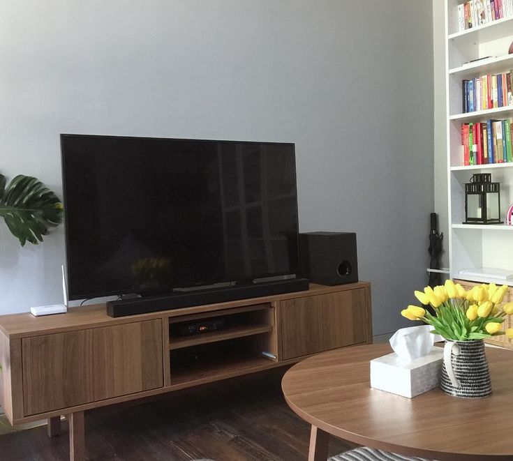 a flat screen tv sitting on top of a wooden entertainment center in a living room