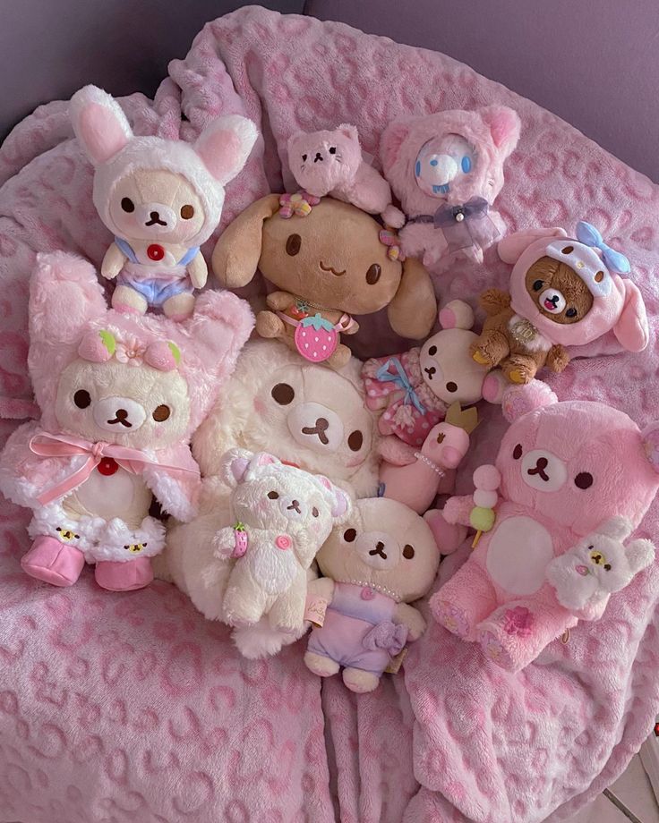 a bunch of stuffed animals on a pink blanket