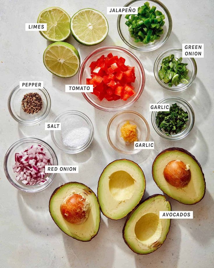 the ingredients for an avocado salad laid out on a white counter top with their names