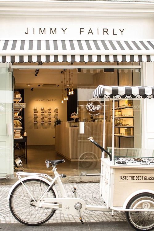 a white bike parked in front of a storefront with an ice cream cart behind it