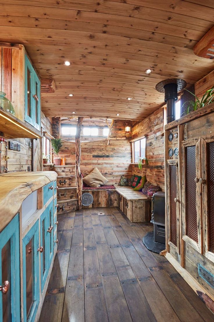 the inside of a log cabin with wood flooring and blue cabinetry on the walls