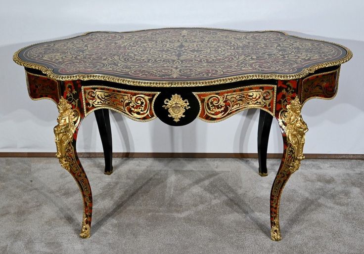 an ornately decorated table with black and gold trimmings on the top, sitting in a room