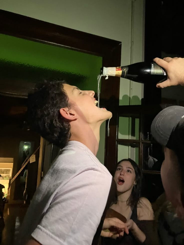 a man that is standing up with a wine bottle in his hand and people around him