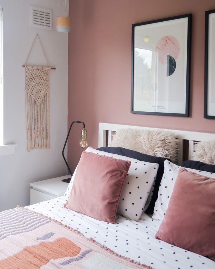 a bedroom with pink walls and white bedding, two framed pictures on the wall