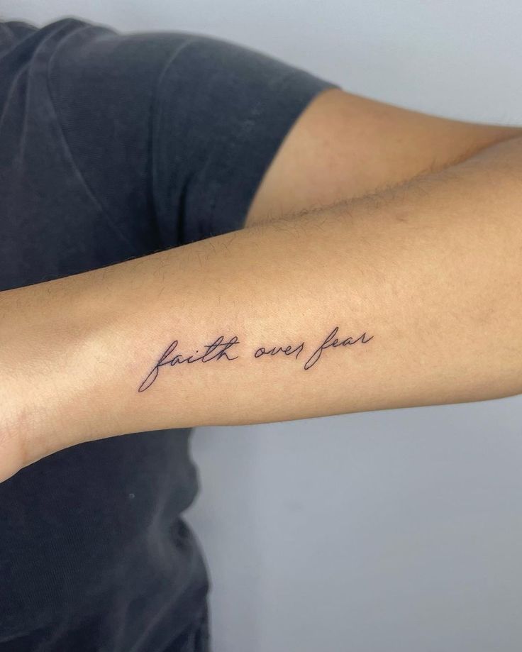 a woman with a tattoo on her arm that says faith and joy in cursive writing