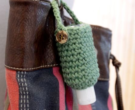 a crocheted handbag hanging on a wall with a bottle in the pocket