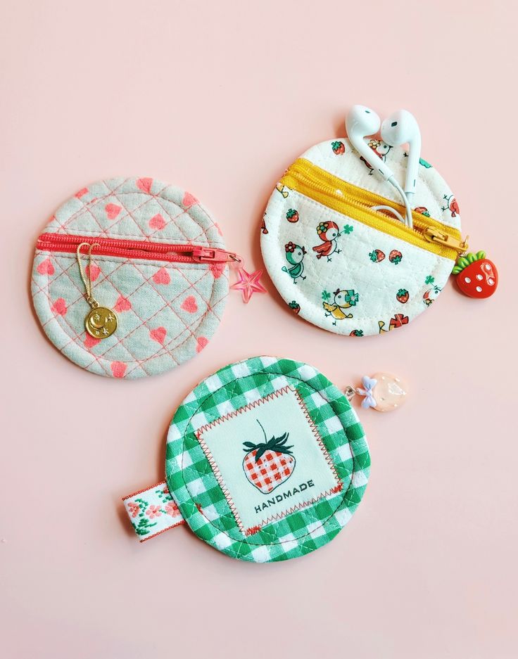 three small purses on a pink surface with one in the shape of a strawberry