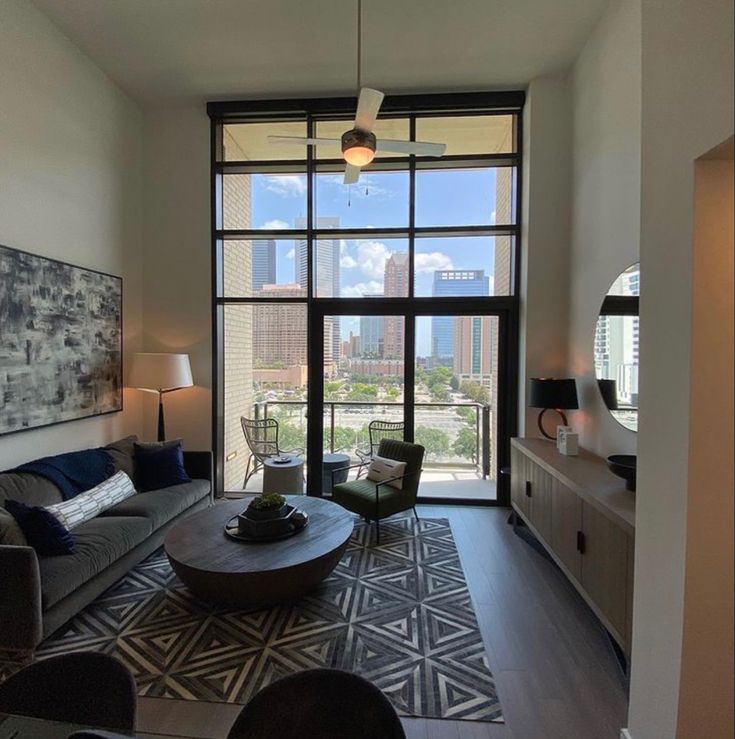 a living room filled with furniture and a large window overlooking the cityscape in the distance