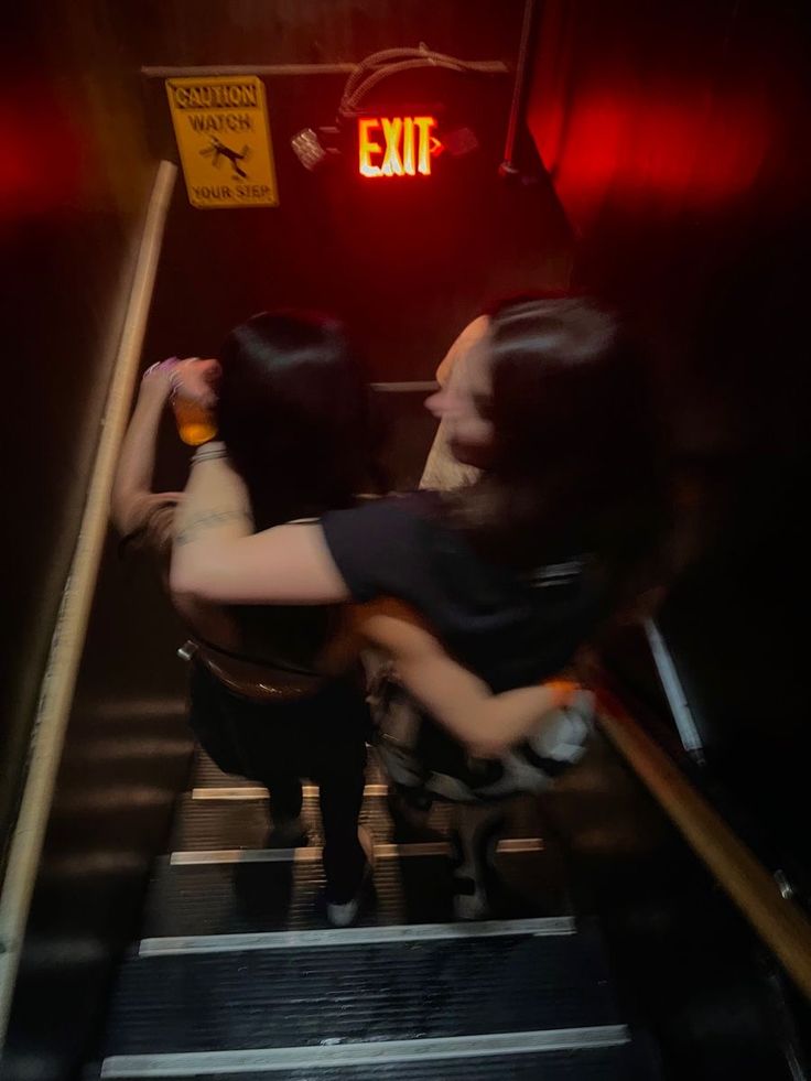 two people walking up an escalator with their arms in the air and holding onto each other