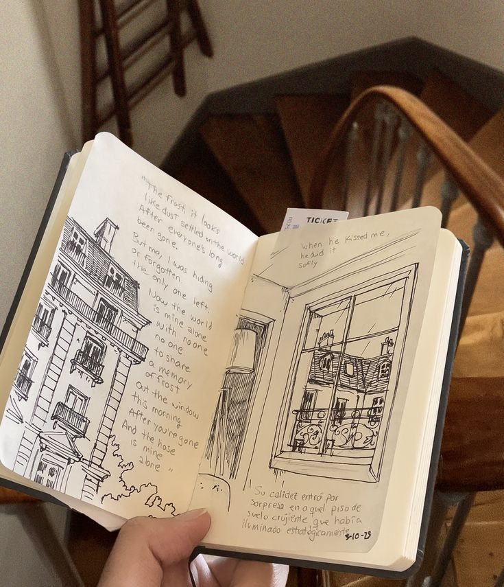 Hand holding open sketchbook with fine line black ink drawings of Paris buildings and roofs and poetic excerpts from Mitski's music. The background features a charming wooden stairway in Paris. Fine Lines Drawing, Paris Line Drawing, Sketch Inspo Aesthetic, Drawing Asthetic Picture, Fine Line Sketches, Journal Drawings Sketchbooks, Journal Drawings Aesthetic, Craft Sketchbook, Artists Notebook