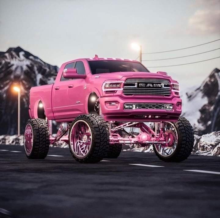 a pink truck is parked on the road in front of some snow covered mountains and lights