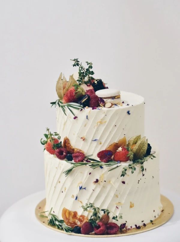 a three tiered cake with berries and leaves on it