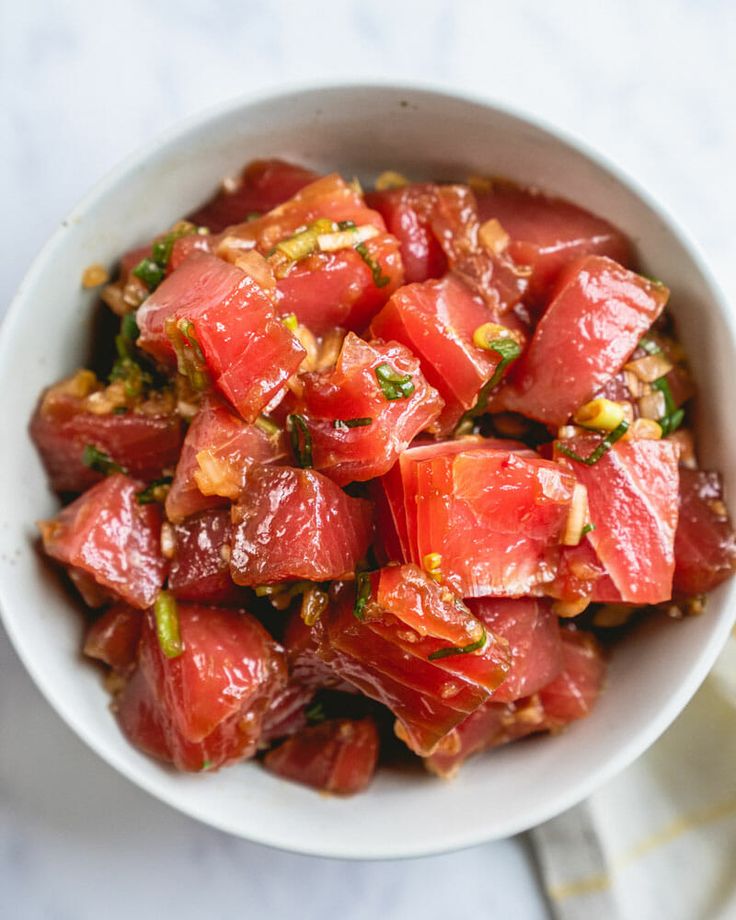 a white bowl filled with watermelon and pistachio salad on top of a marble table