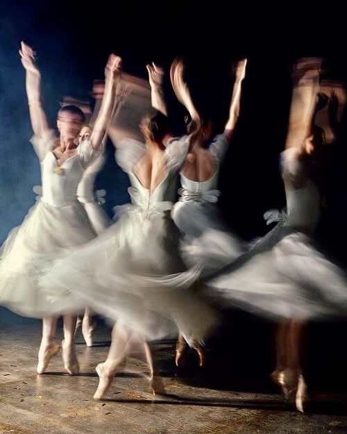 several ballet dancers in white tutu skirts are dancing with their hands up and arms outstretched