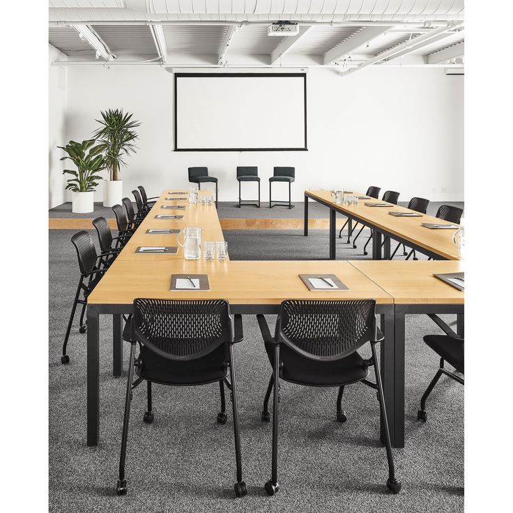 an empty conference room is set up with tables and chairs for people to sit at