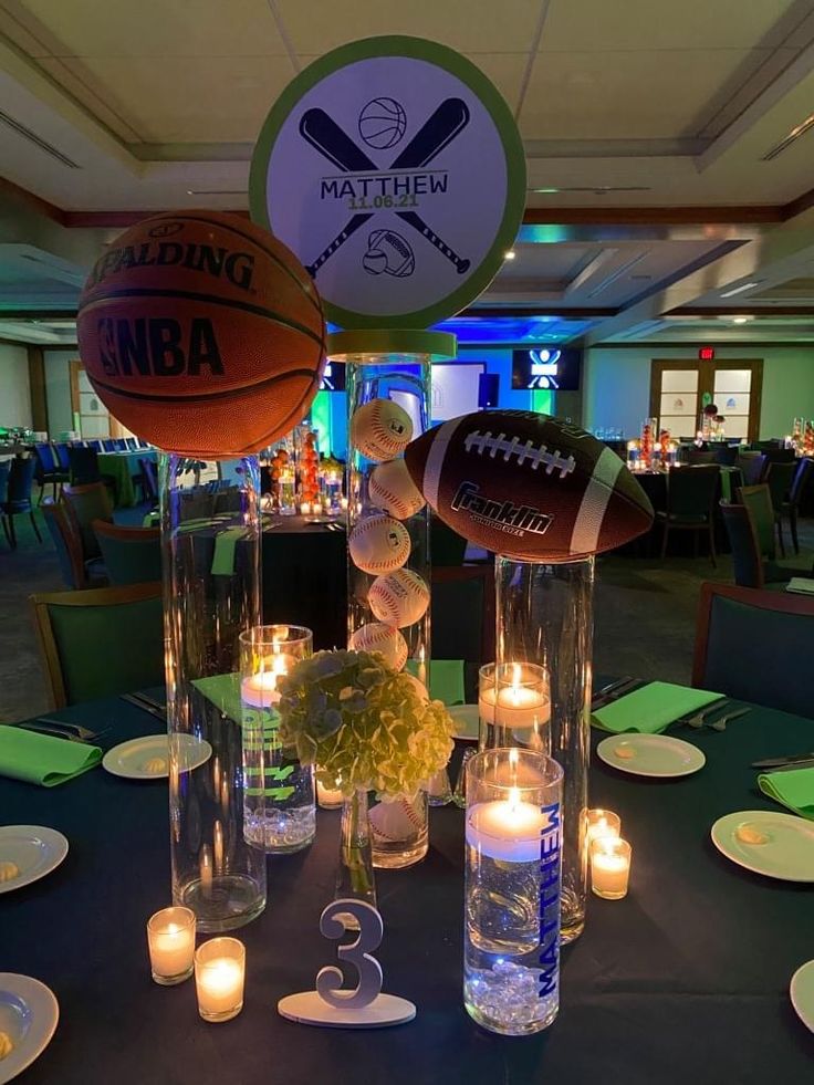 a sports themed centerpiece with candles and footballs on the table in front of it