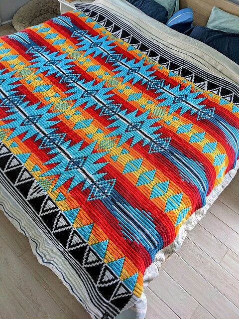 an image of a bed with a colorful blanket on it