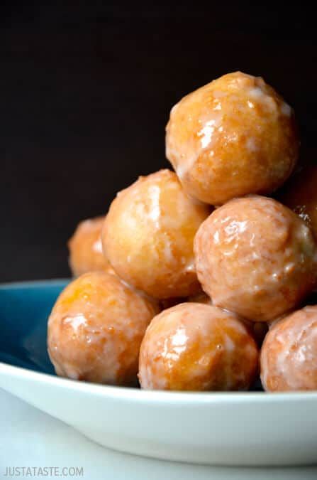 a white bowl filled with donuts sitting on top of a table next to a blue plate