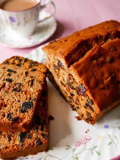 two slices of fruitcake on a plate with a cup and saucer in the background