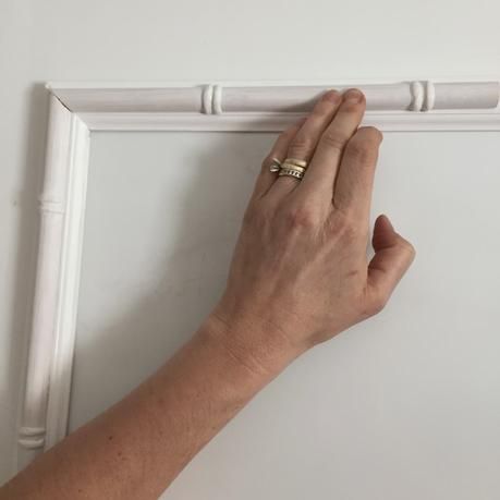 a person's hand holding onto a white frame