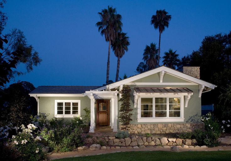 a house that is lit up at night with palm trees in the front yard and landscaping around it