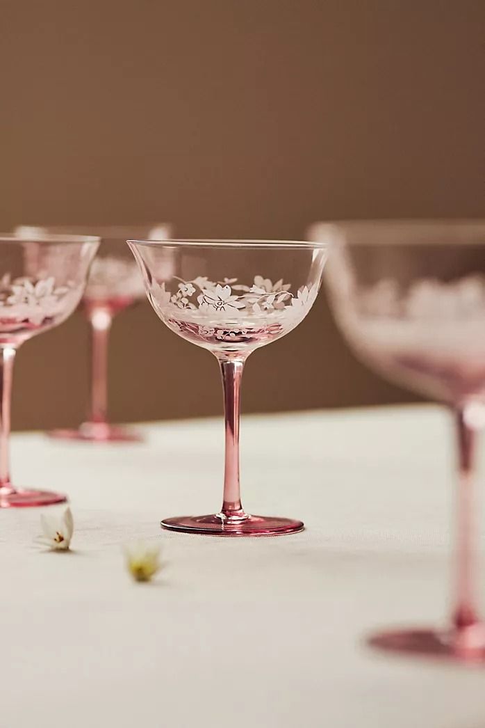 four wine glasses sitting on top of a table next to each other with flowers in them