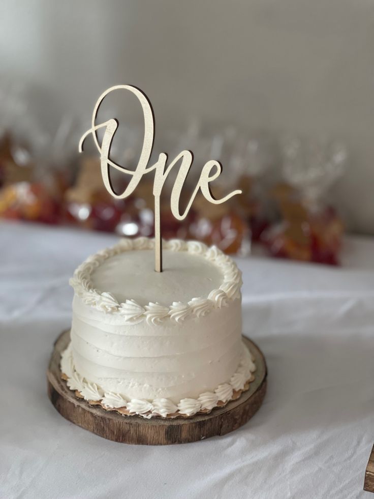 a cake with the word one on it is sitting on a white tablecloth covered table