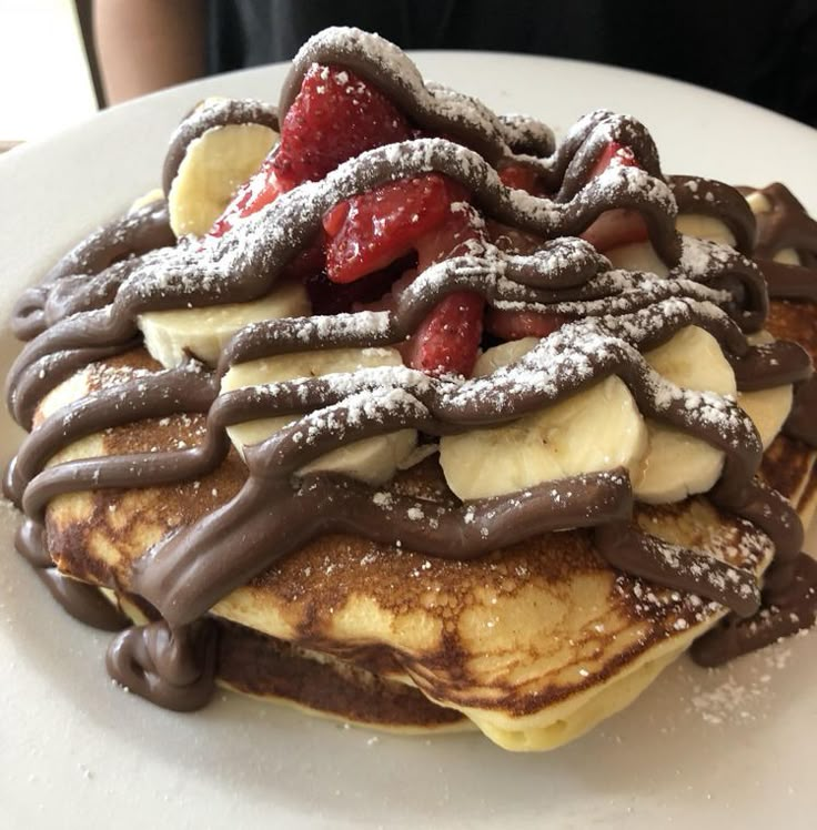 chocolate covered pancakes topped with bananas and strawberries