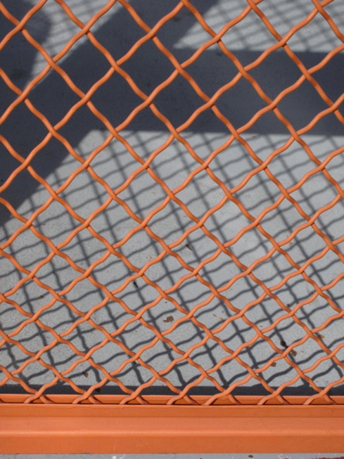 an orange metal fence on the side of a building