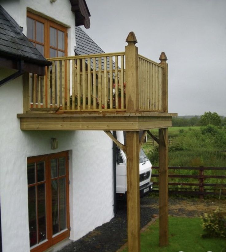 a house with a car parked in front of it and a wooden deck on the outside