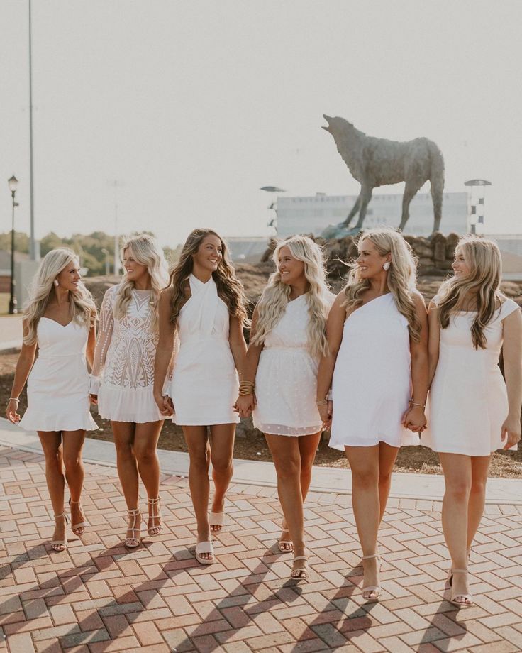 a group of women standing next to each other on a brick floor in front of a statue