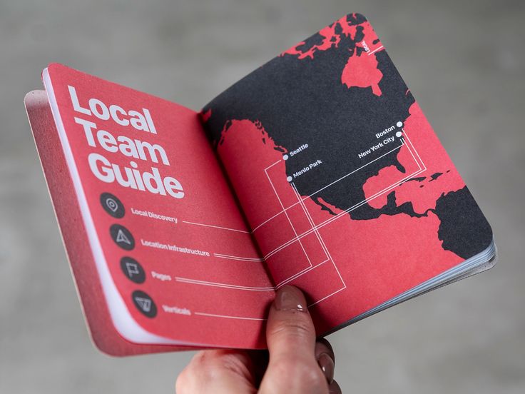 a hand holding a red book with the words local team guide on it