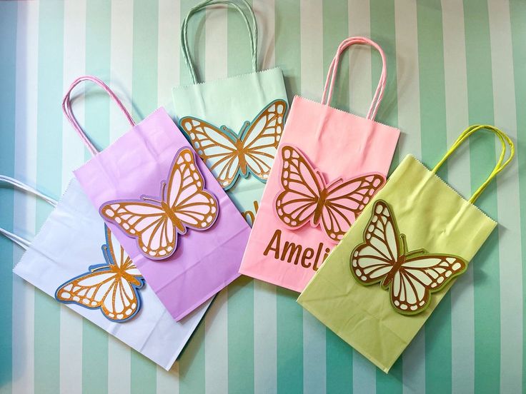 four colorful bags with butterflies on them sitting on a table next to striped wallpaper