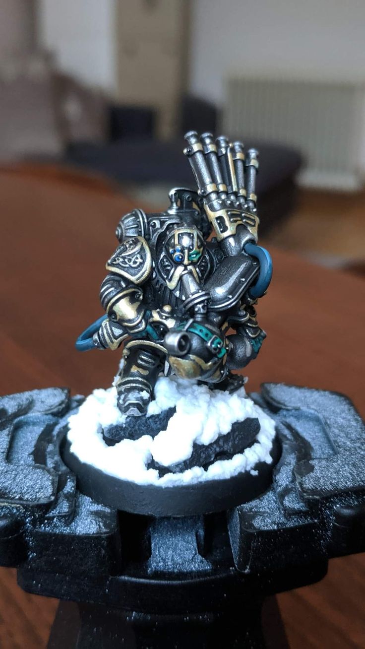 a miniature warhammer is sitting on top of a black piece of furniture with white snow