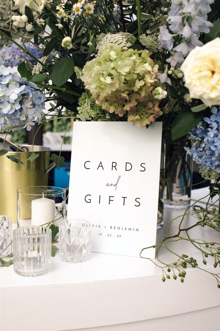 there is a sign that says cards and gifts next to some flowers on the table