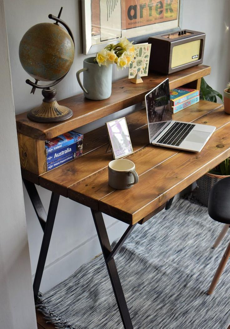 a wooden desk topped with a laptop computer next to a vase filled with yellow flowers