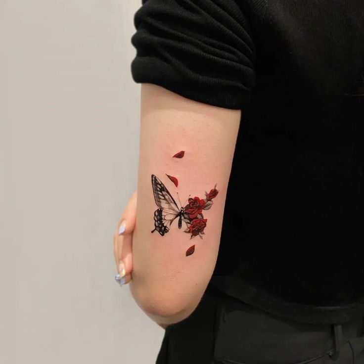 a woman with a tattoo on her arm has a butterfly and rose petals on it