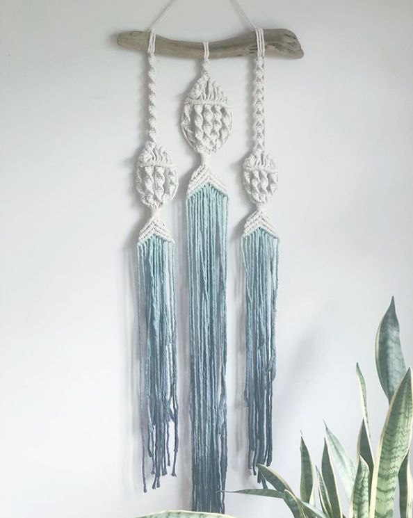 three macrame dream catchers hanging on a wall next to a potted plant